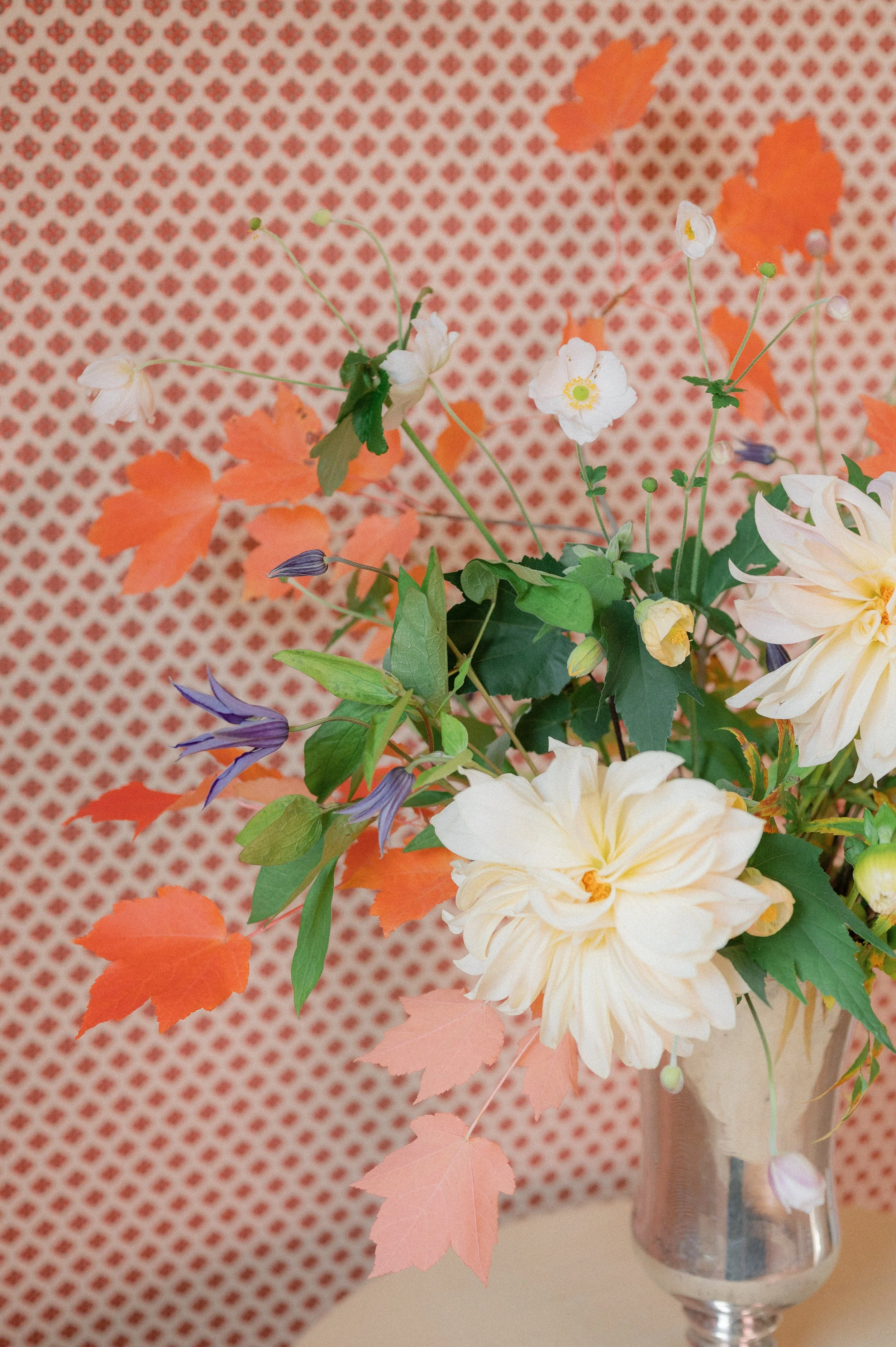 Floral arrangement by Hattie McLean with dahlias, flowering maple, clematis, anemones, and red maple leaves