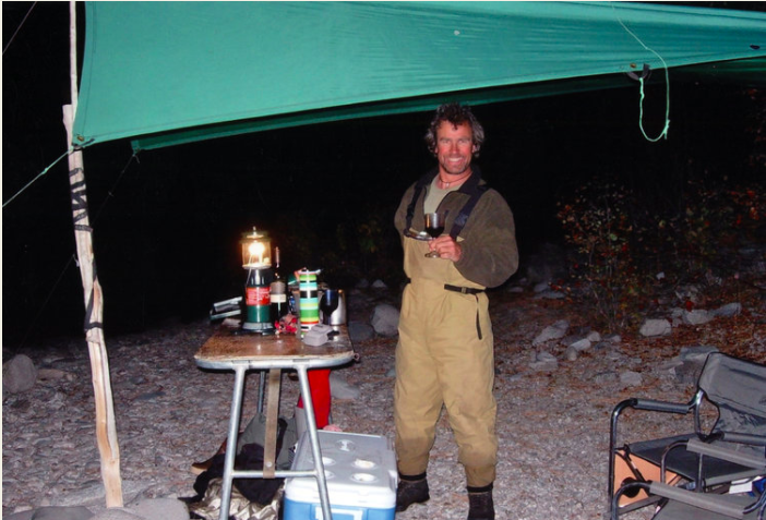 Guy toasting with a glass of wine in fishing waders