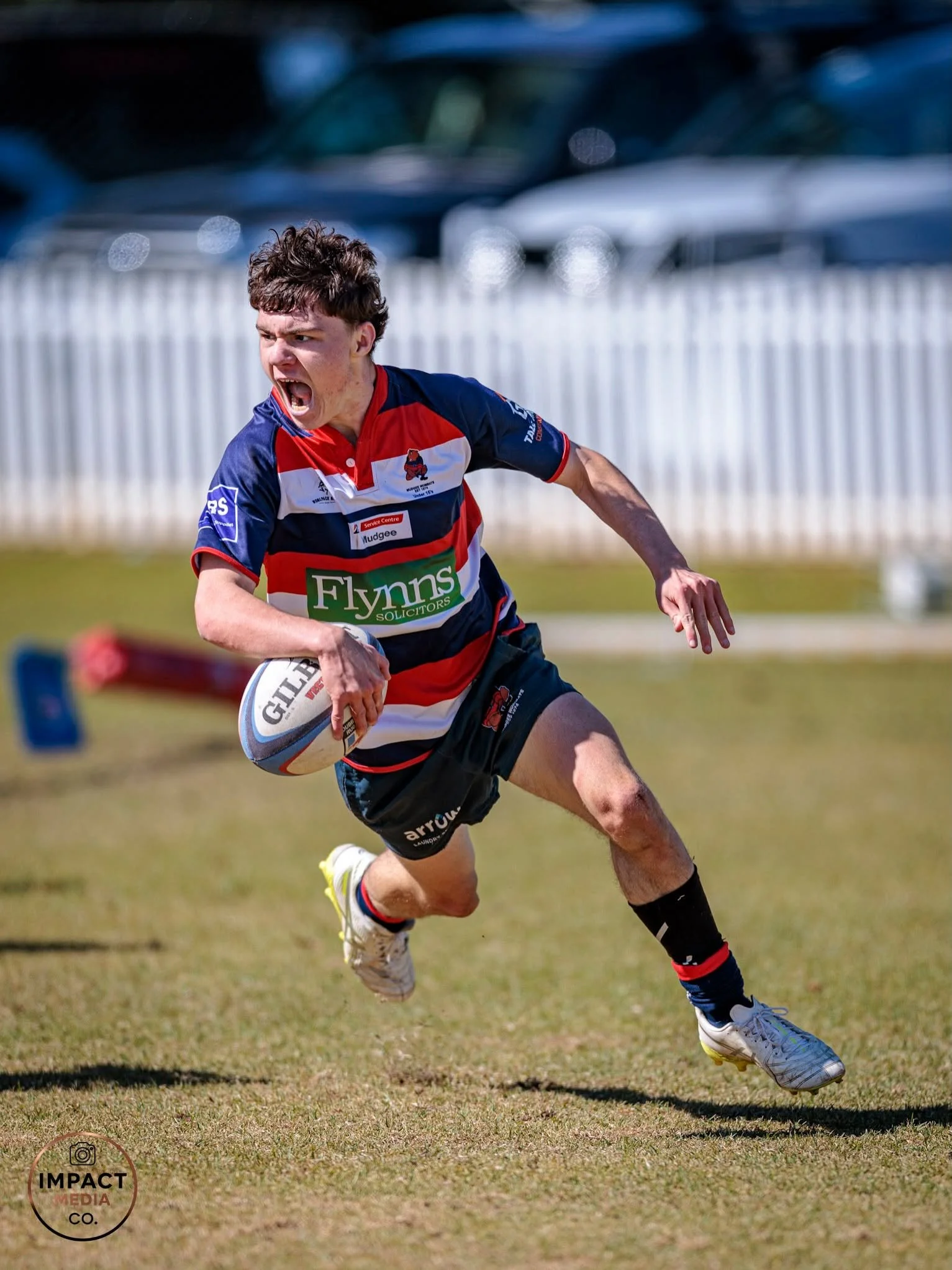 Junior rugby league player runs with the ball during a match.