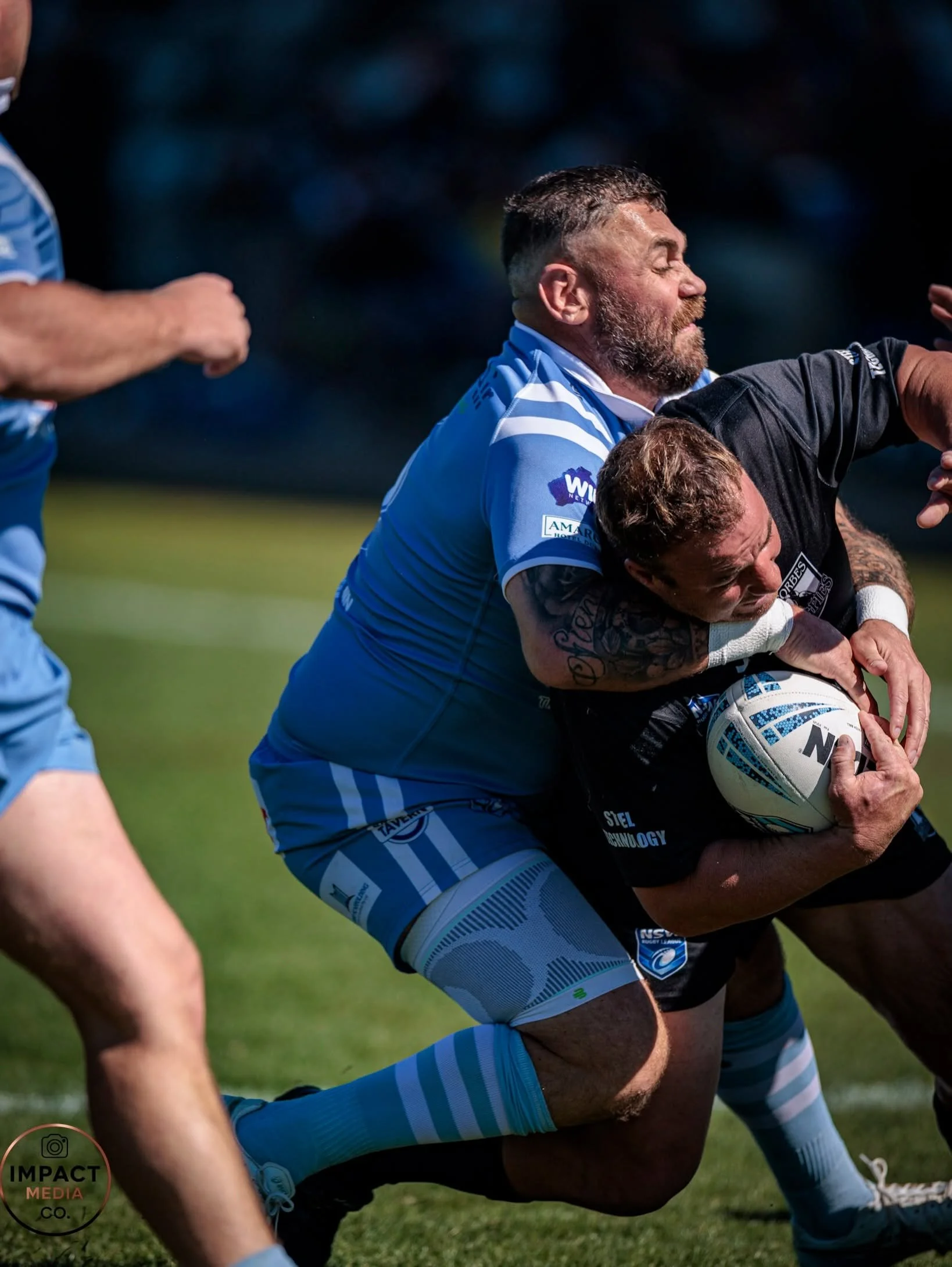 Rugby league players contest a scrum on a grass field.