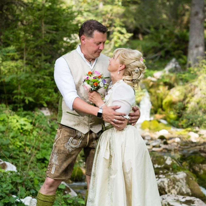 Trachtiges Hochzeitspaar im Wald küssend.