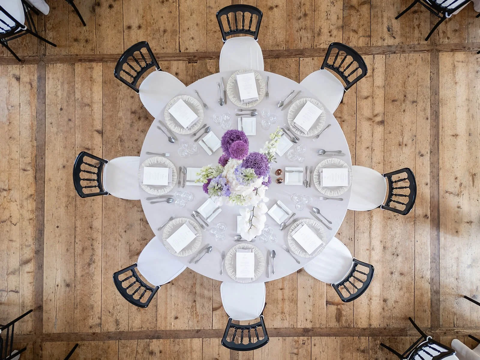 Round table setting at Walpersdorf Castle for a wedding, with floral decorations by Emil Doll, menu cards and elegant tableware.