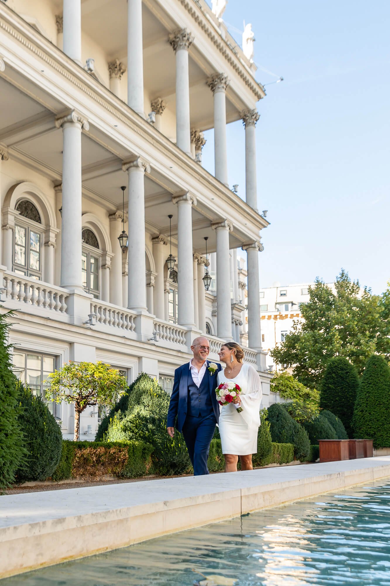 Wedding couple strolls in the garden of Palais Coburg Vienna