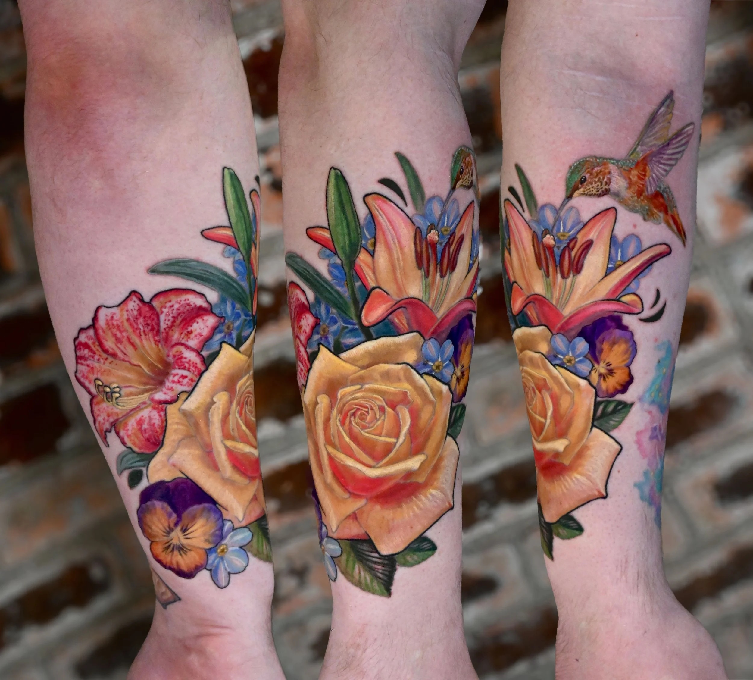 Colorful tattoo of flowers and hummingbirds on person's forearms, with a brick wall background.