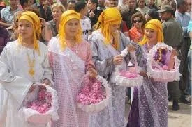 Four girls wearing yellow head coverings and holding baskets of roses