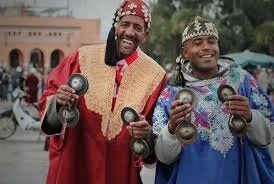 Two men playing small metal musical instruments with their hands