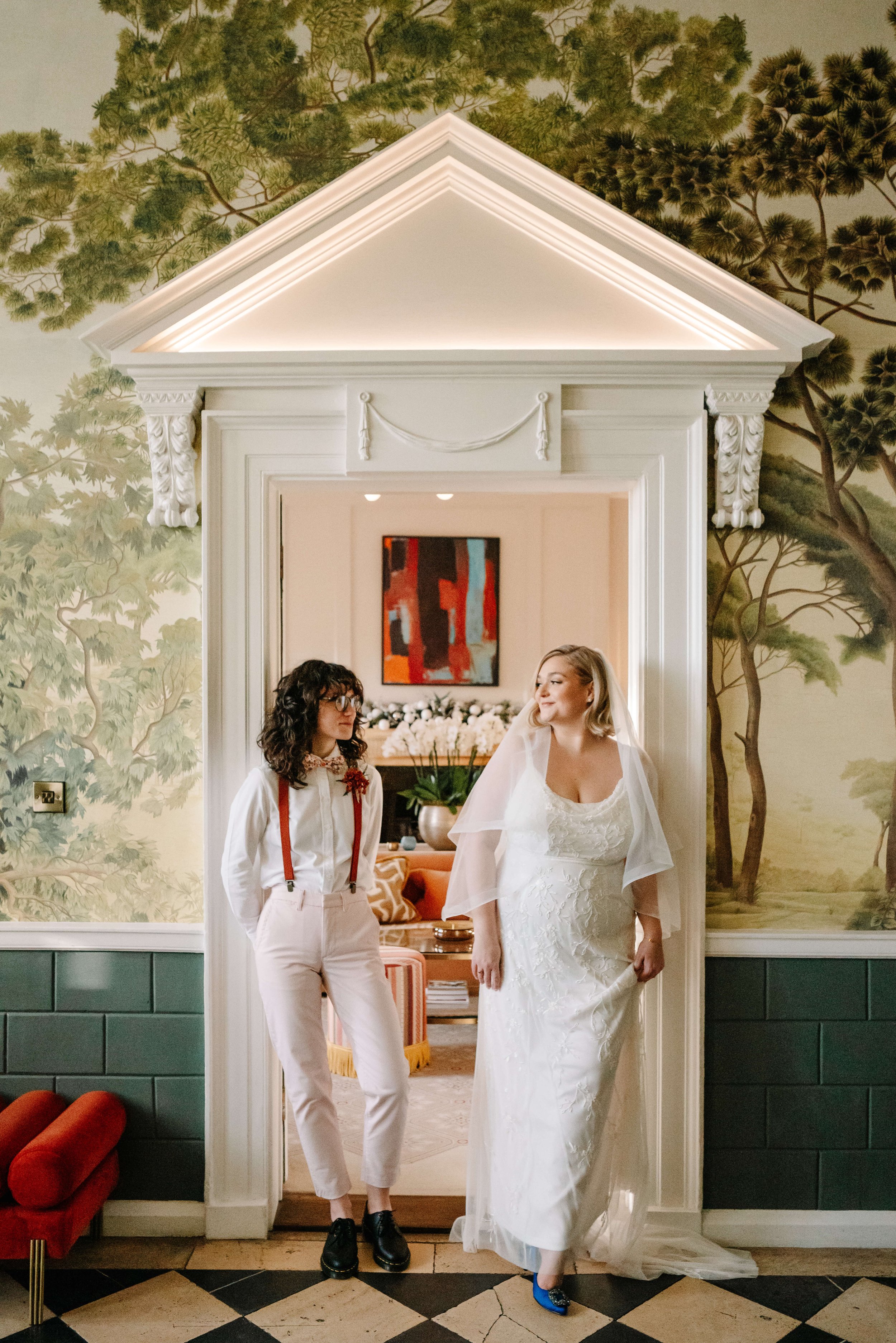 Lesbian couple standing in hallway of grand building on wedding day - London wedding photographer
