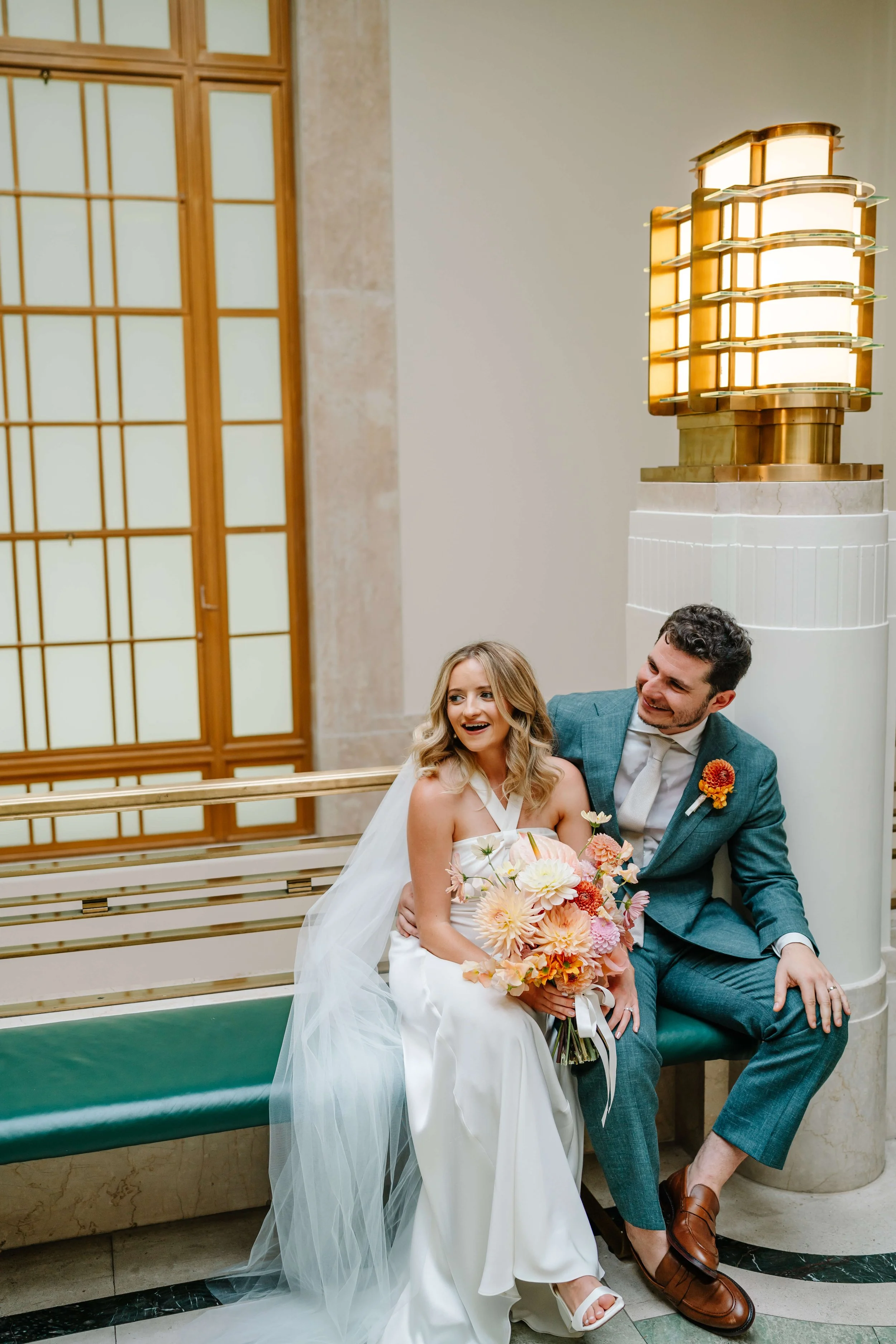 couple sitting in Hackney Town Hall on their wedding day with bright florals