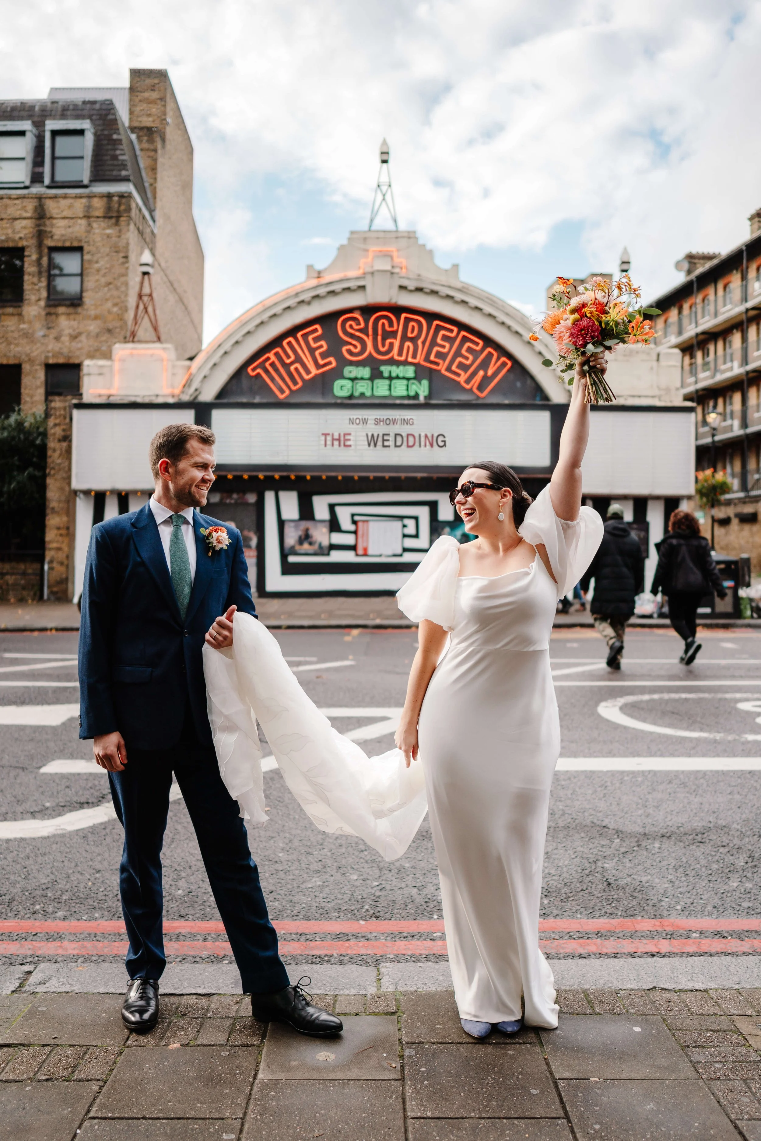 fun wedding couple pose outside Islington's "screen on the green"