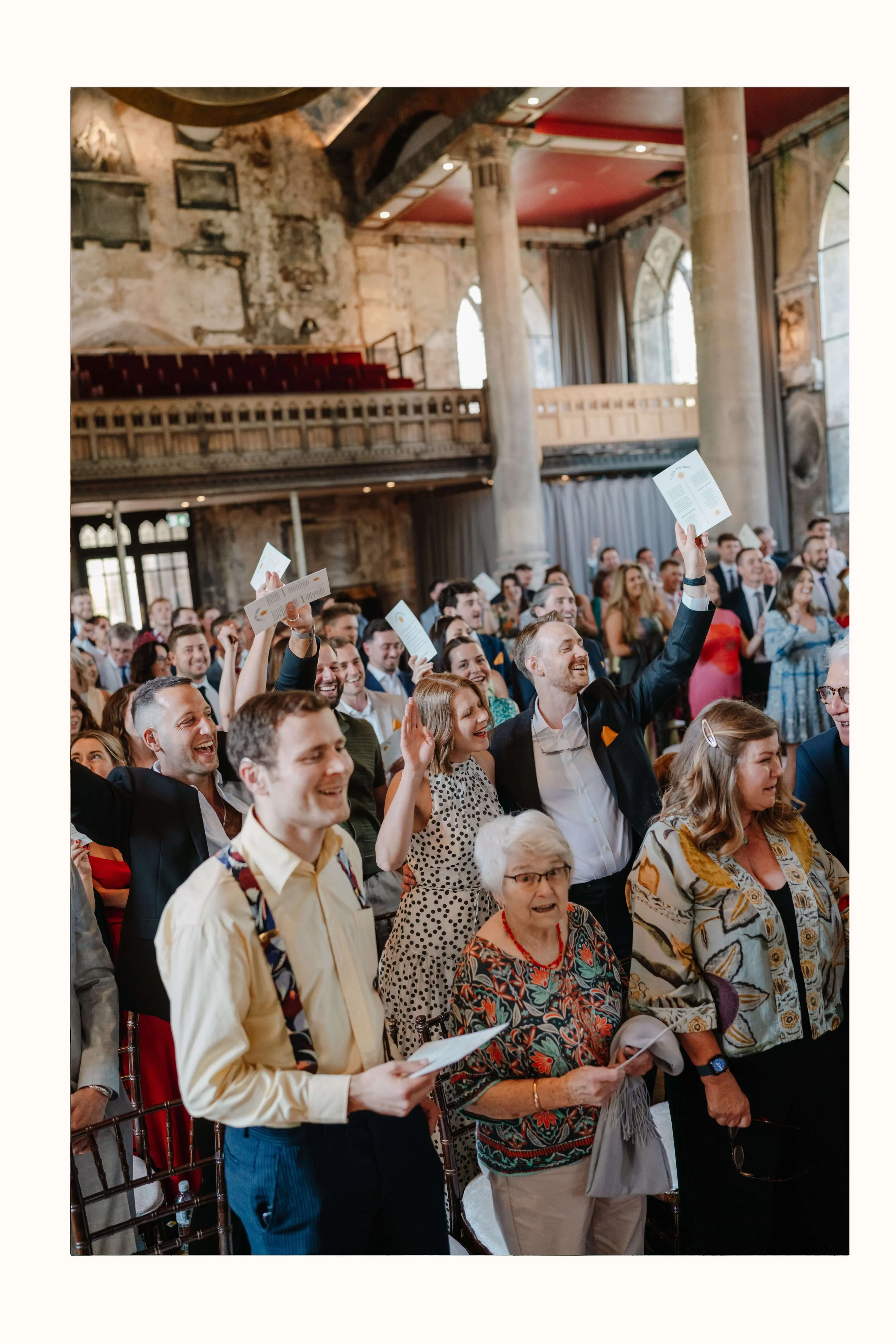 Guests at a wedding at The Mount Without are singing during the ceremony, smiling and cheering