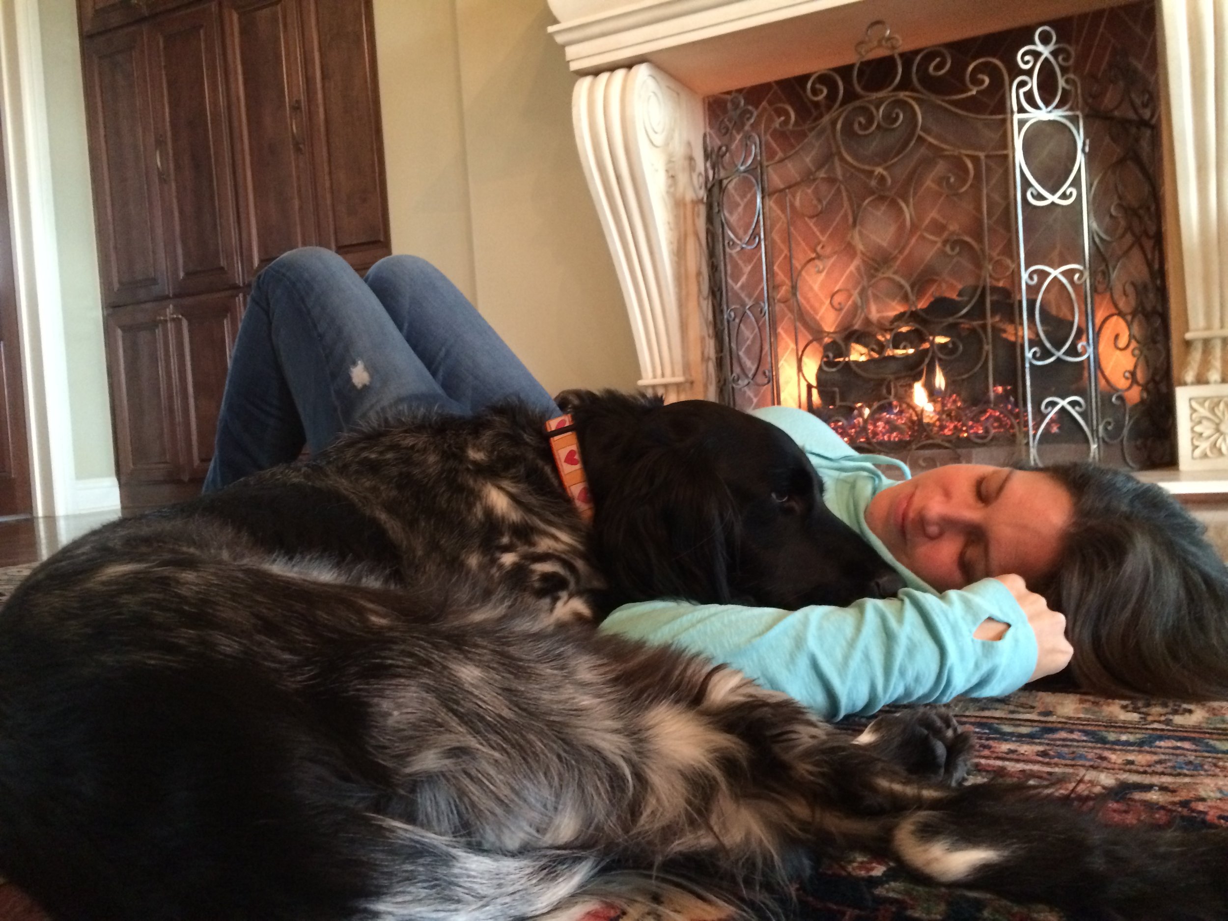 Woman lying in front of a fireplace with a dog.