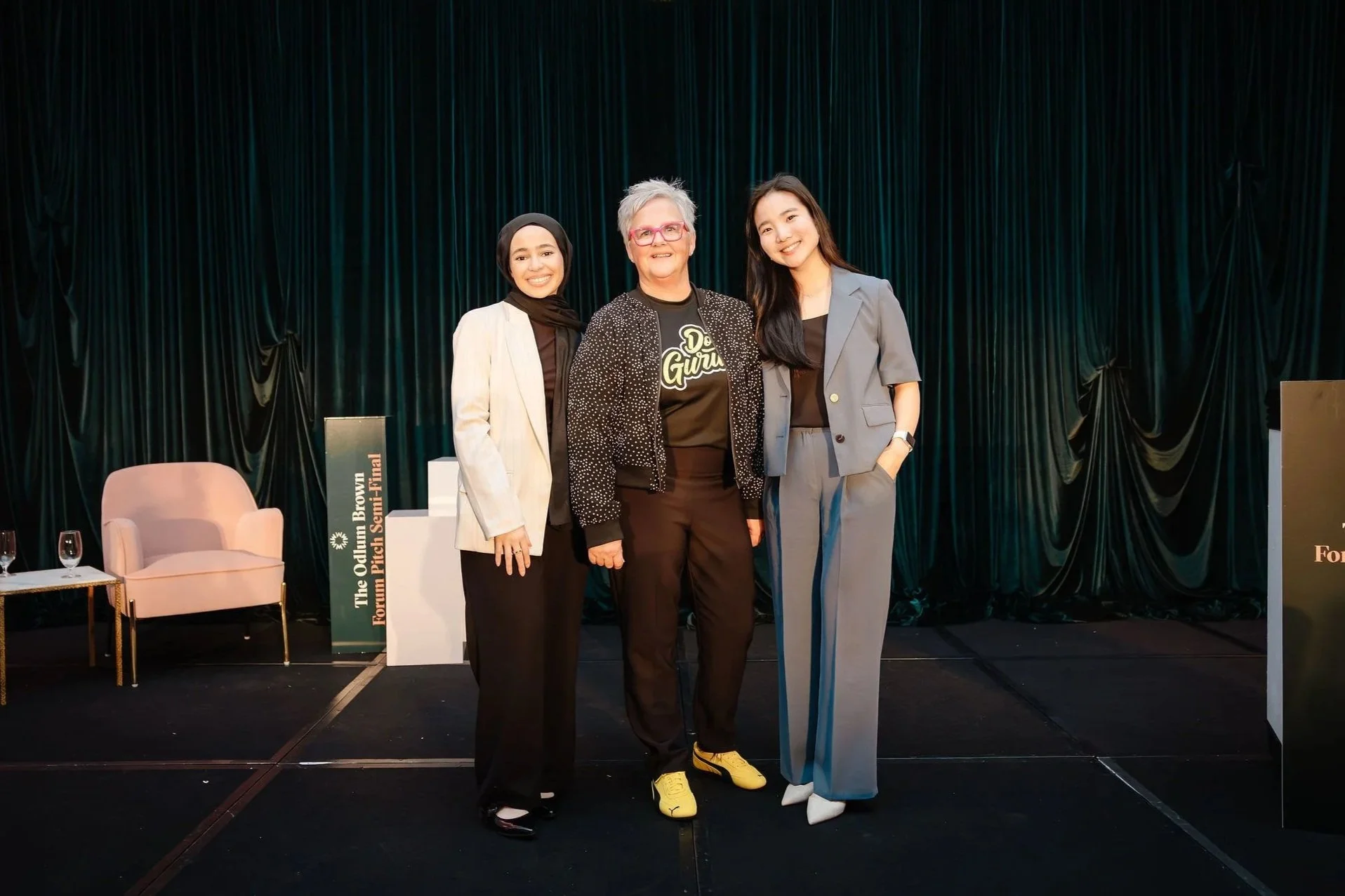 Three women are standing together on a stage
