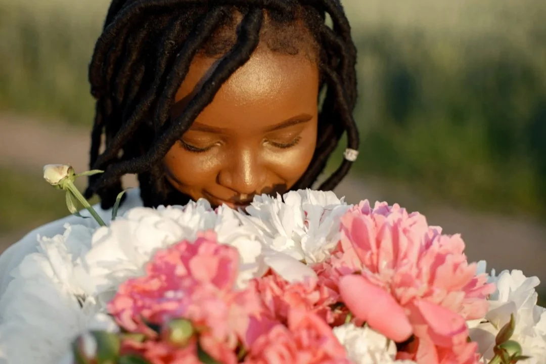 Black woman smelling flowers.