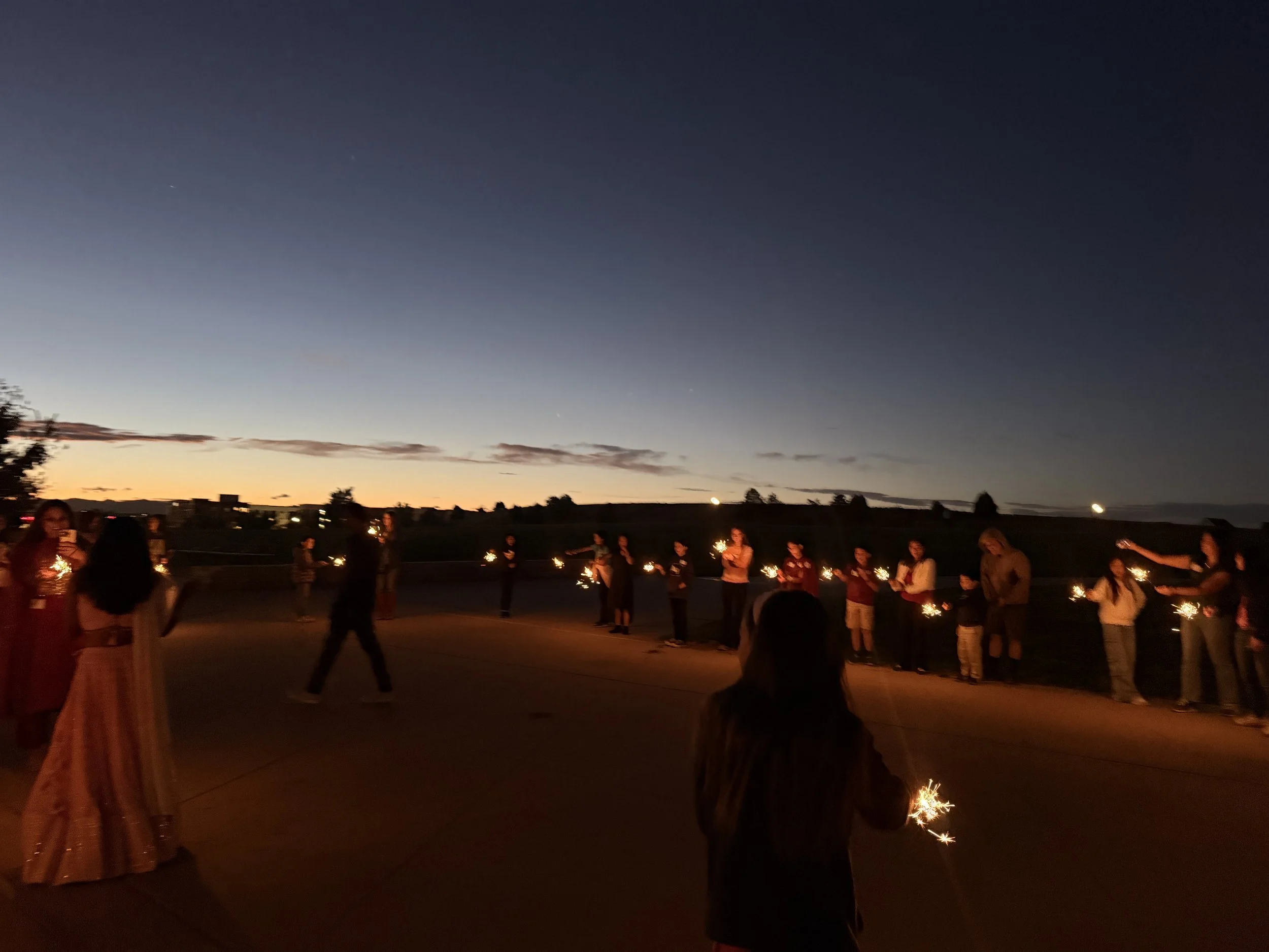  AGI students and family light sparklers at night at AGI Diwali CelebrAsian 