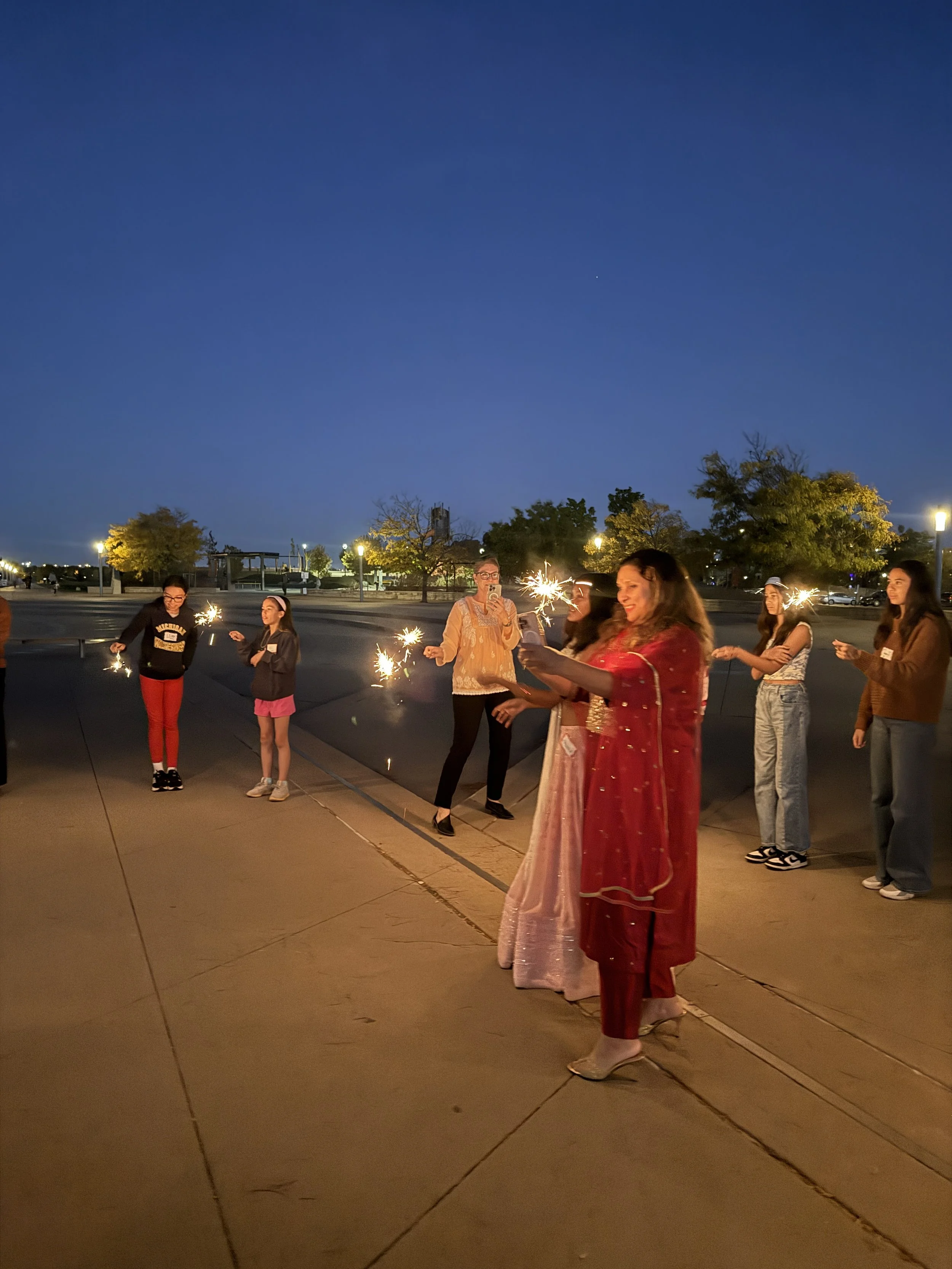  AGI students and family light sparklers at night at AGI Diwali CelebrAsian 