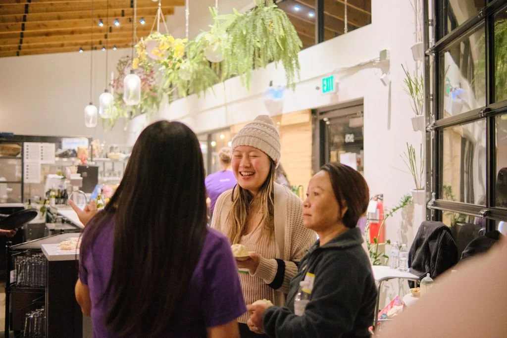 Community members speaking with AGI staff at at AppreciAsian 2025 hosted at Yuan Wonton 