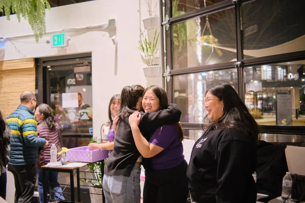  AGI staff hug and smile at AGI AppreciAsian 2025 hosted at Yuan Wonton 