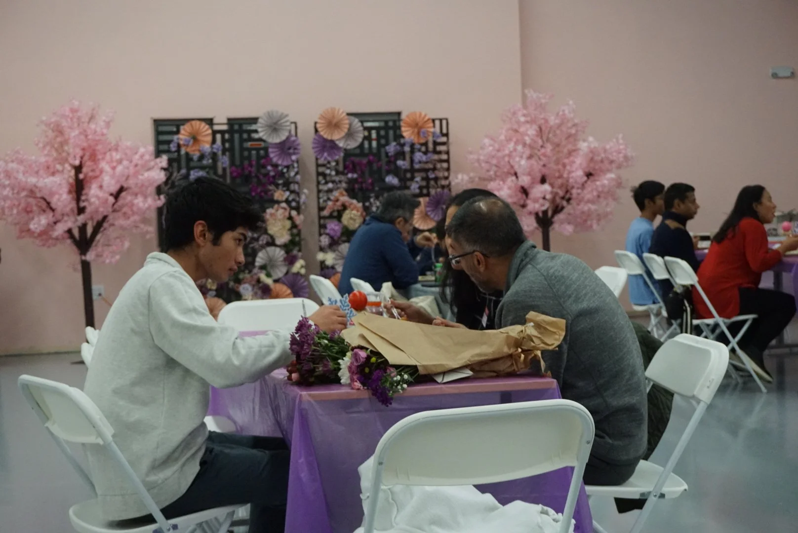  Family sitting at table with purple table cloths at CACEN’s Social Fabric Hub for AGI’s Holiday Social 2025 