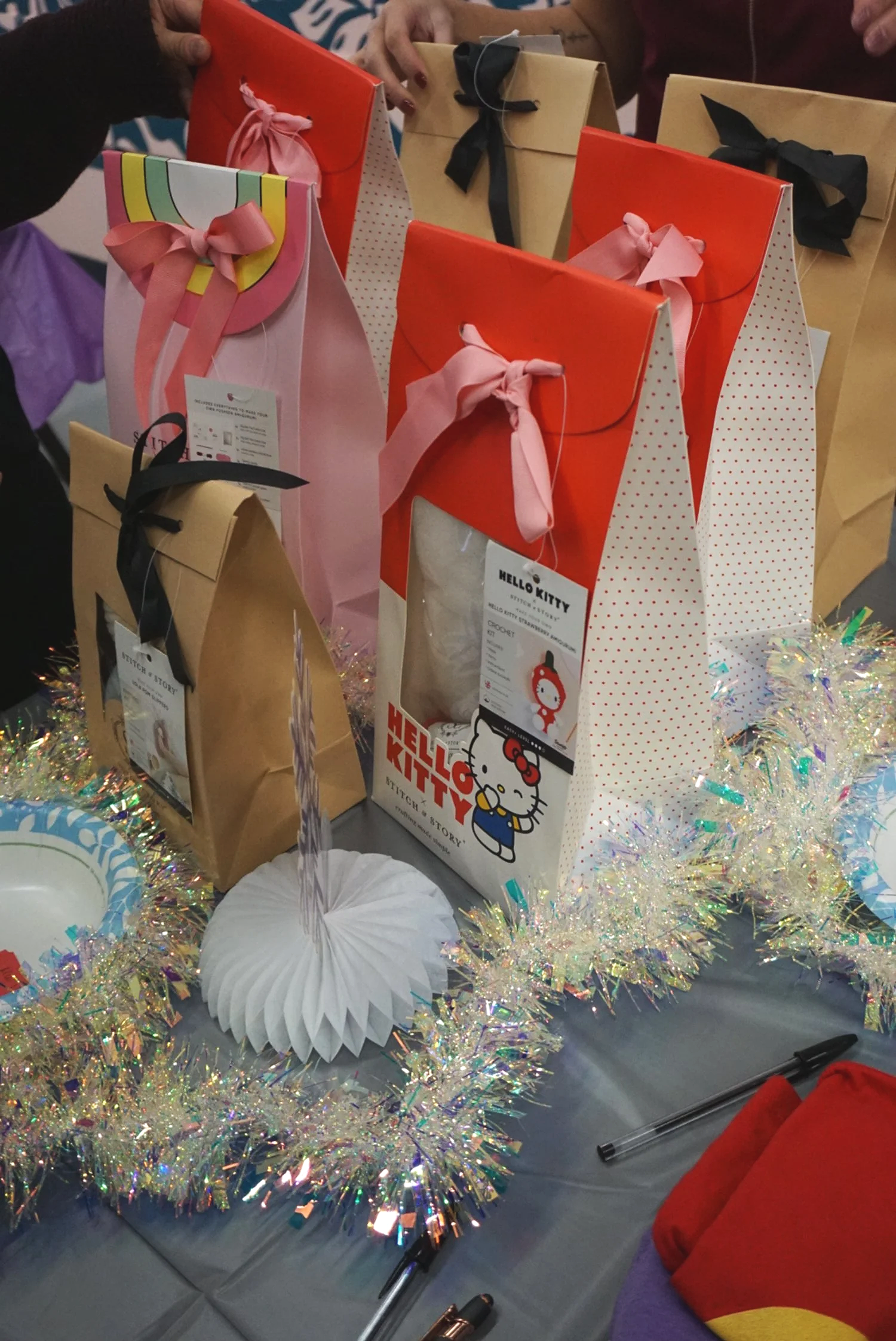  Hello Kitty and Pusheen crochet kits lines up on gray table cloth with tinsel and holiday decor 