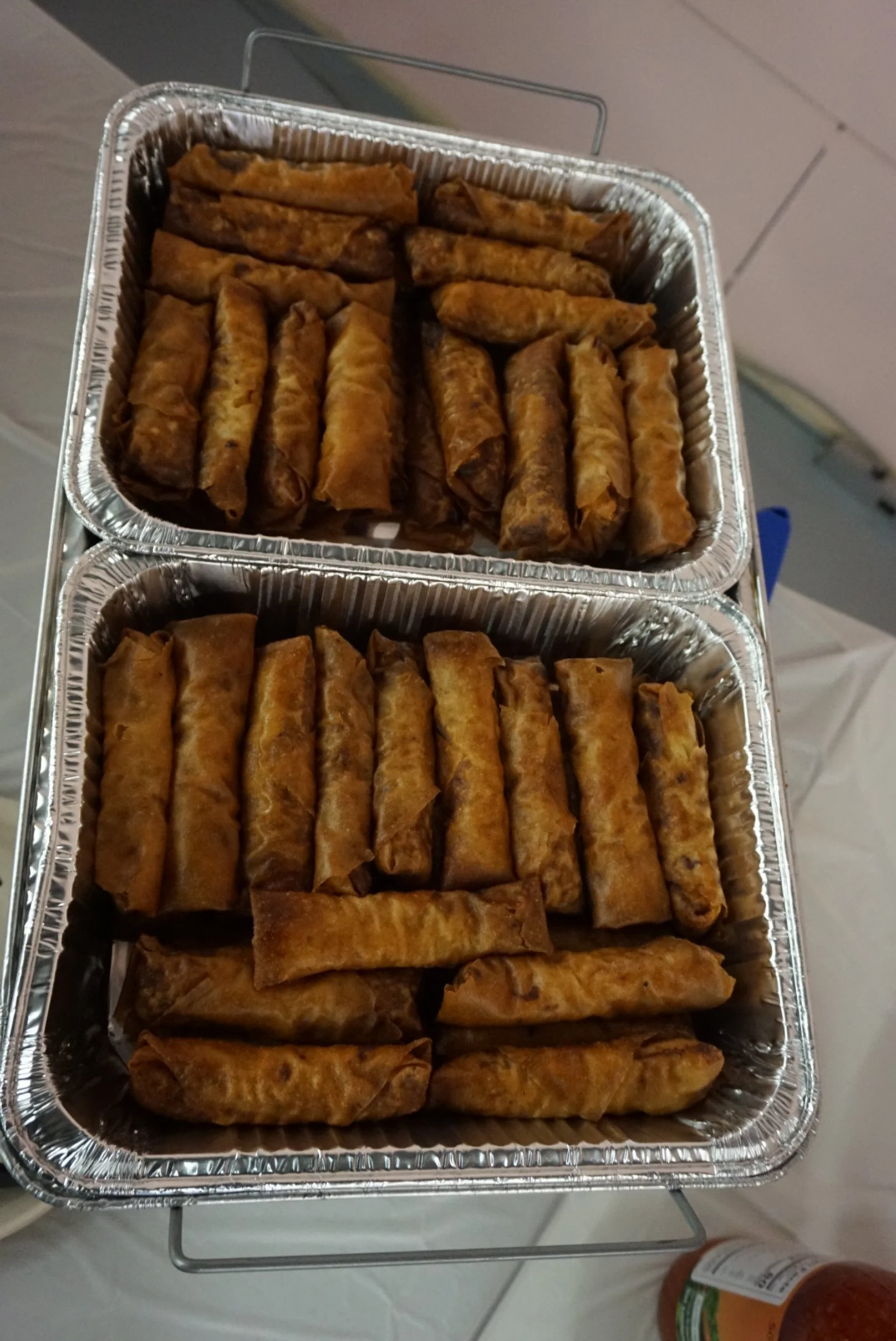  Two tin trays of lumpia on a table 