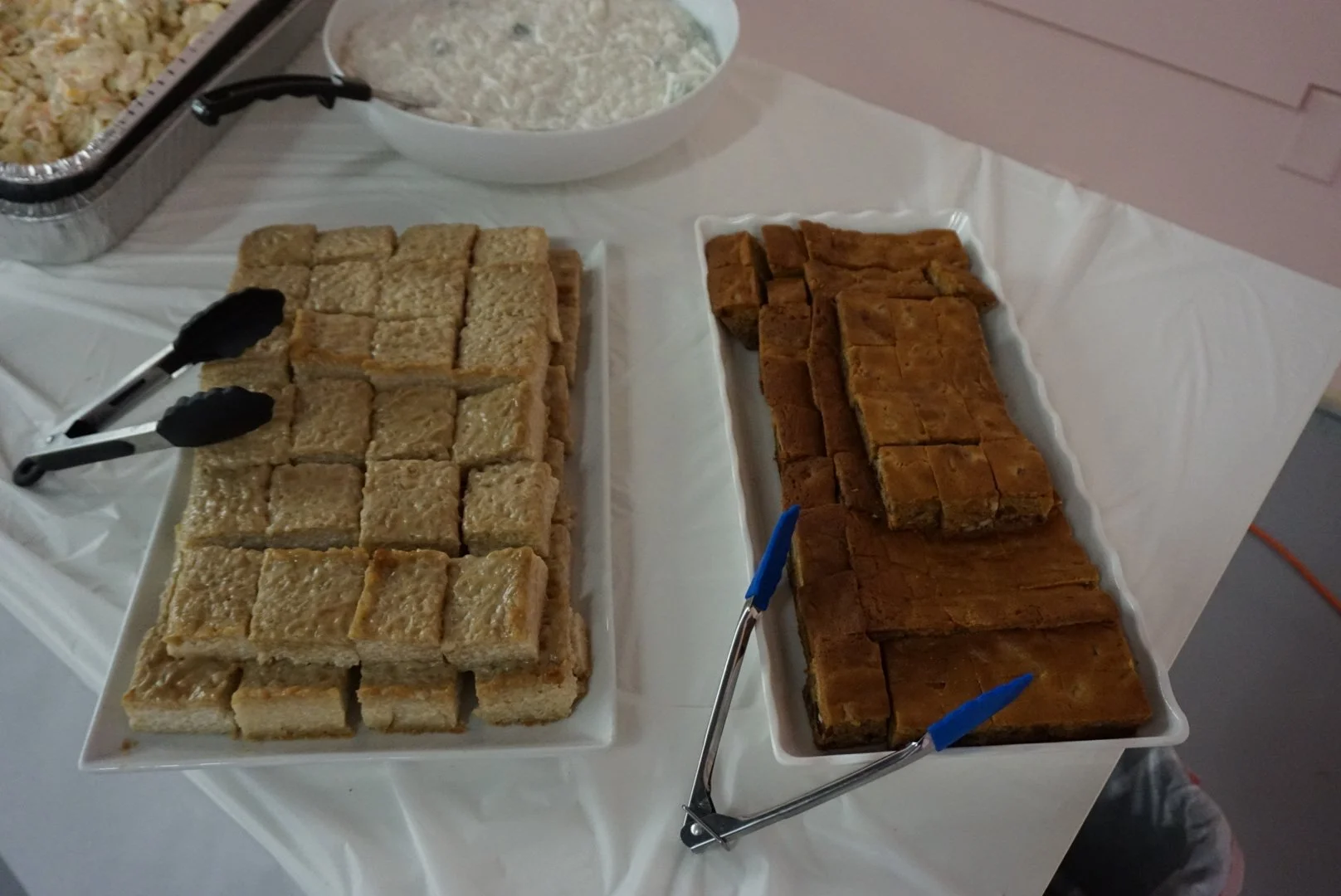  Dishes of biko and Filipino desserts on table with serving utensils rested on top 