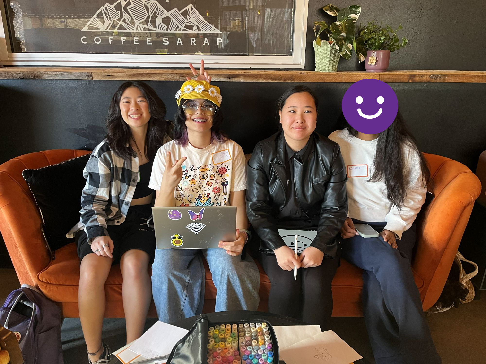  Four students on an orange couch smiling for a photo.  