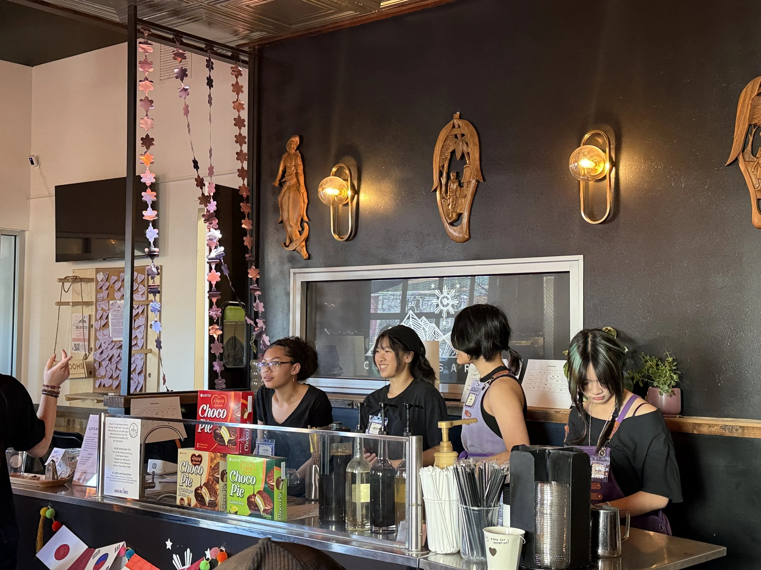  Students stand at indoor coffee cart listening.  