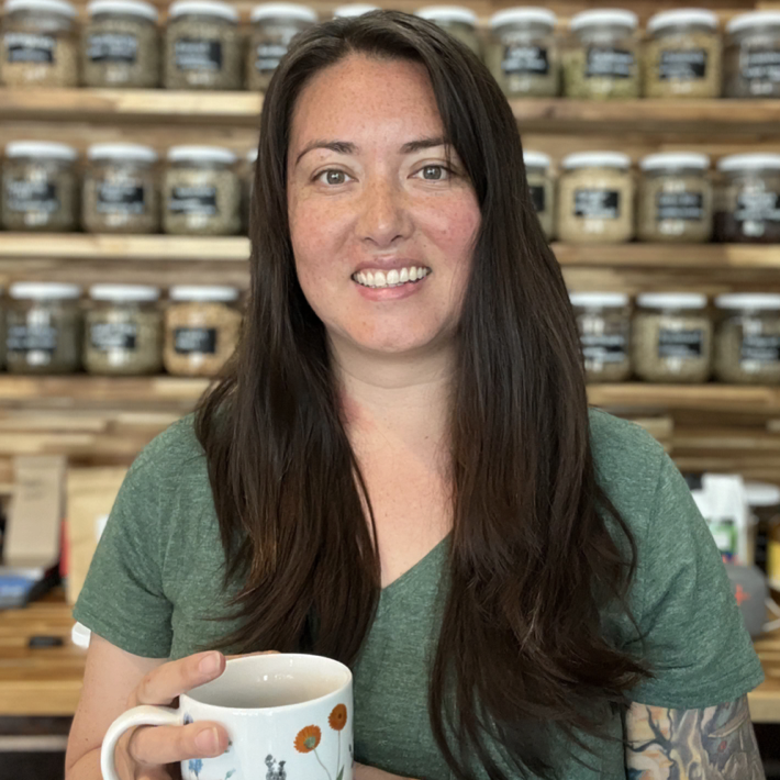 asian american cultural shop owner holding a mug and smiling
