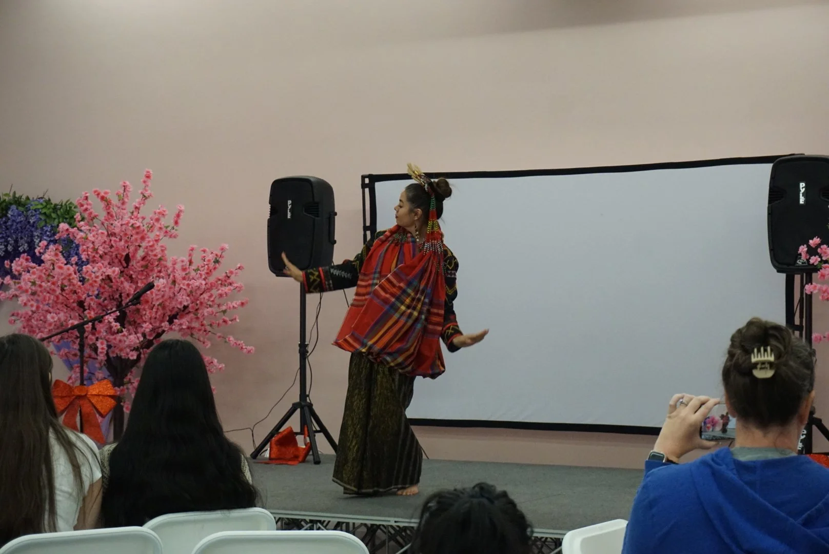 Padayon Cultural FACC performs traditional Filipino Kadal Blelah dance on stage in light pink room with faux floral trees