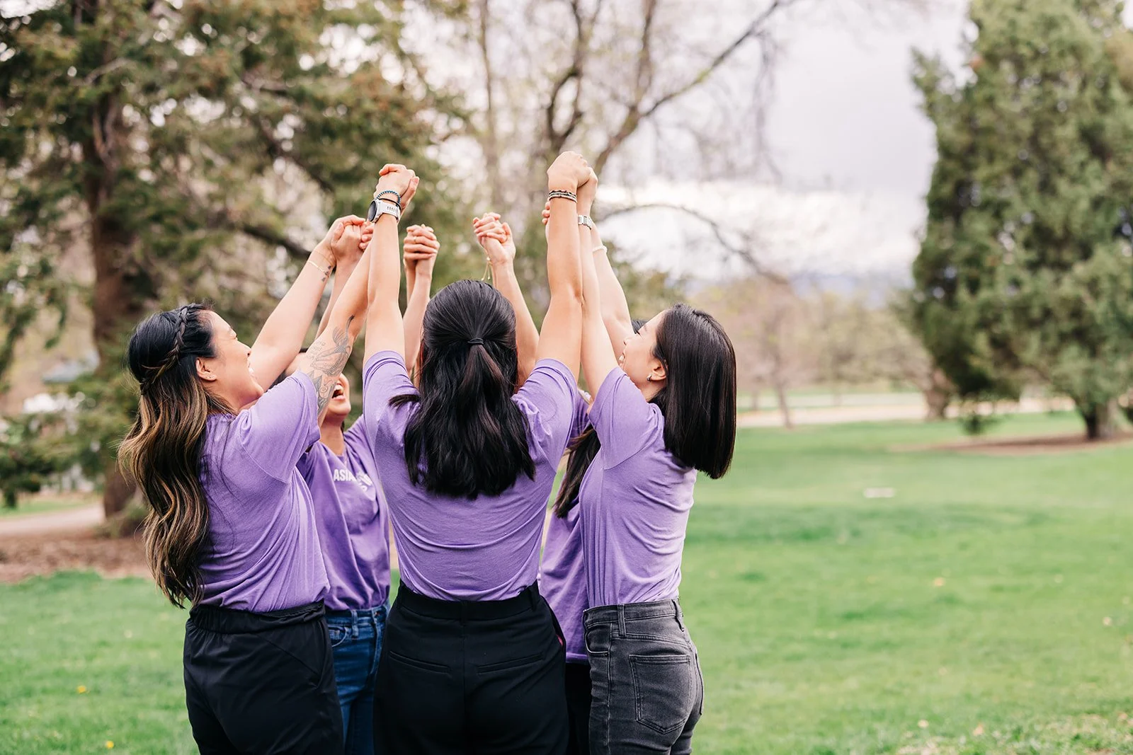 group of asian american adults joyfully putting their hands in the air