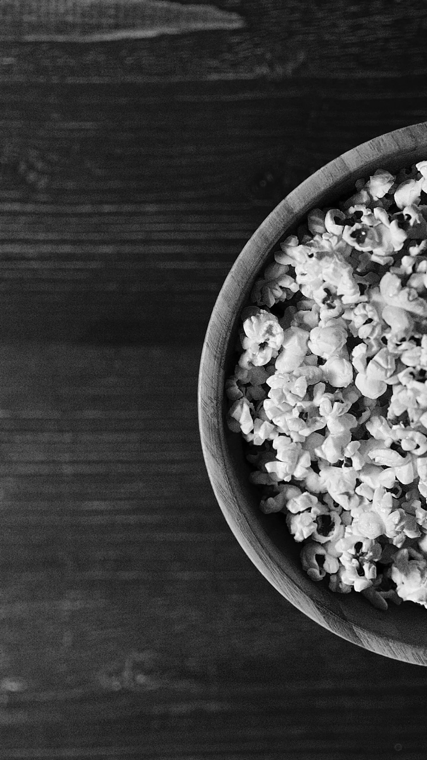 Schale mit Popcorn auf einem Holztisch in Schwarz-Weiß.