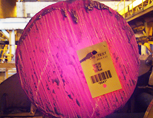 High temperature barcode label applied to a large metal coil in an industrial warehouse or manufacturing environment.