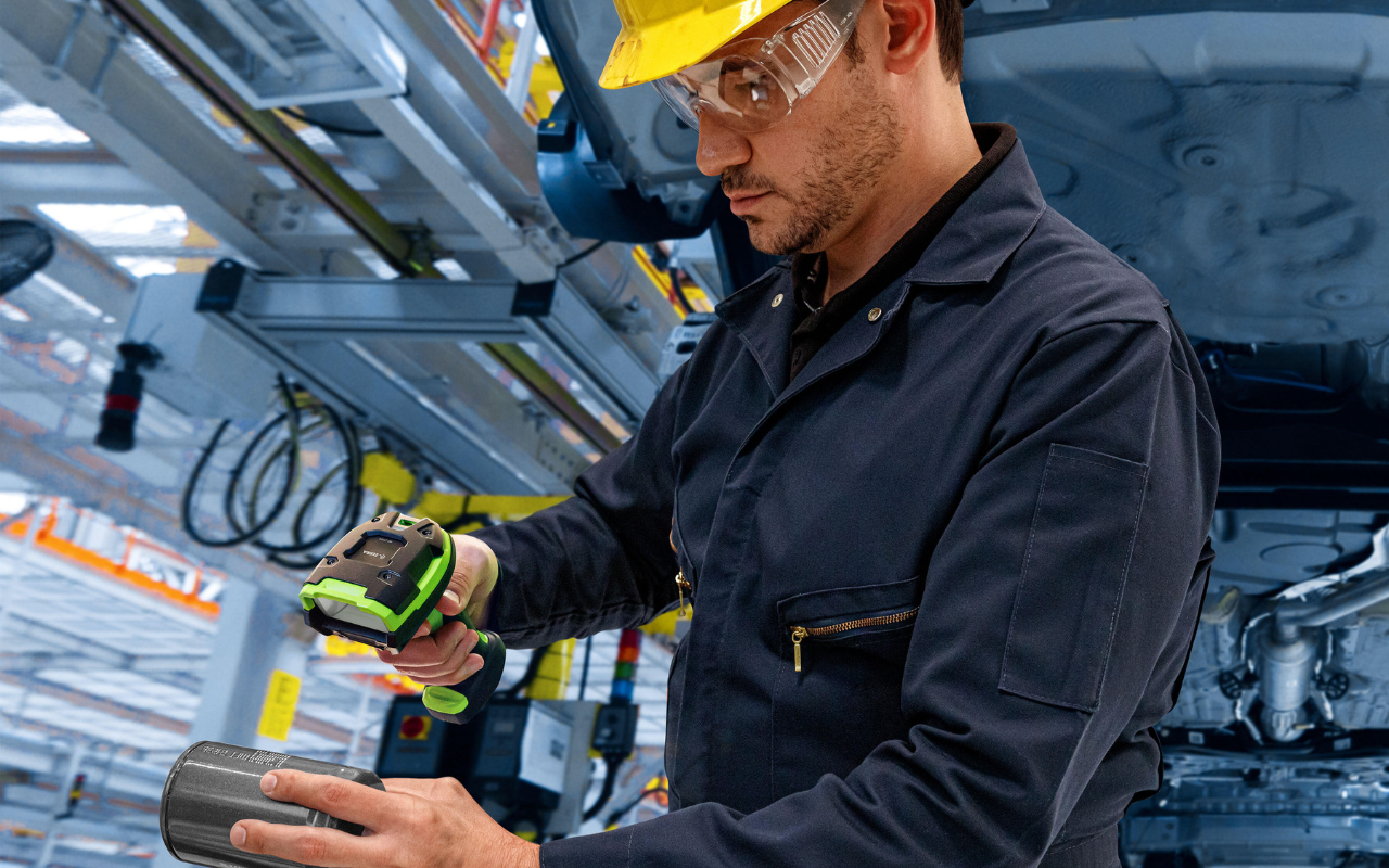 a man on a factory floor using a barcode scanner to scan a part