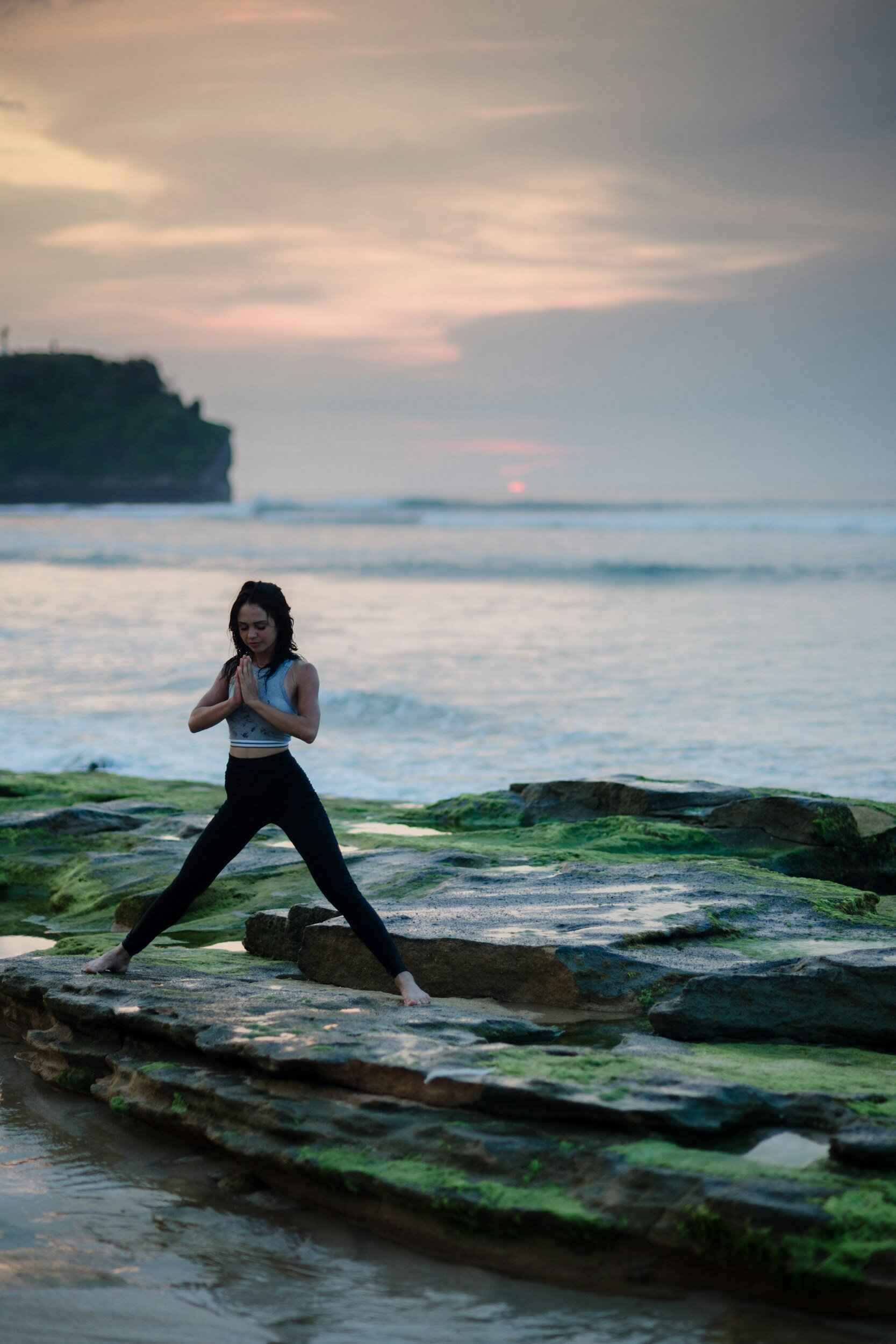 A woman meditating on a rock by the ocean learning to deal with stress.