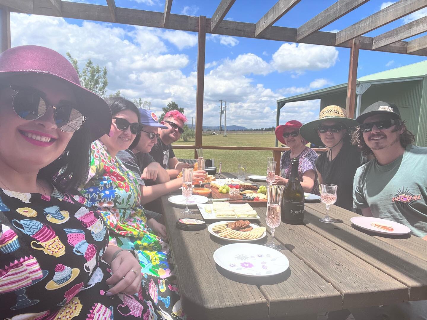 &ldquo;Birthday&rdquo; wine &amp; cheese in the sunshine 

Image: 7 people sitting at a long table in the sunshine on a deck with cheese platter and wine glasses