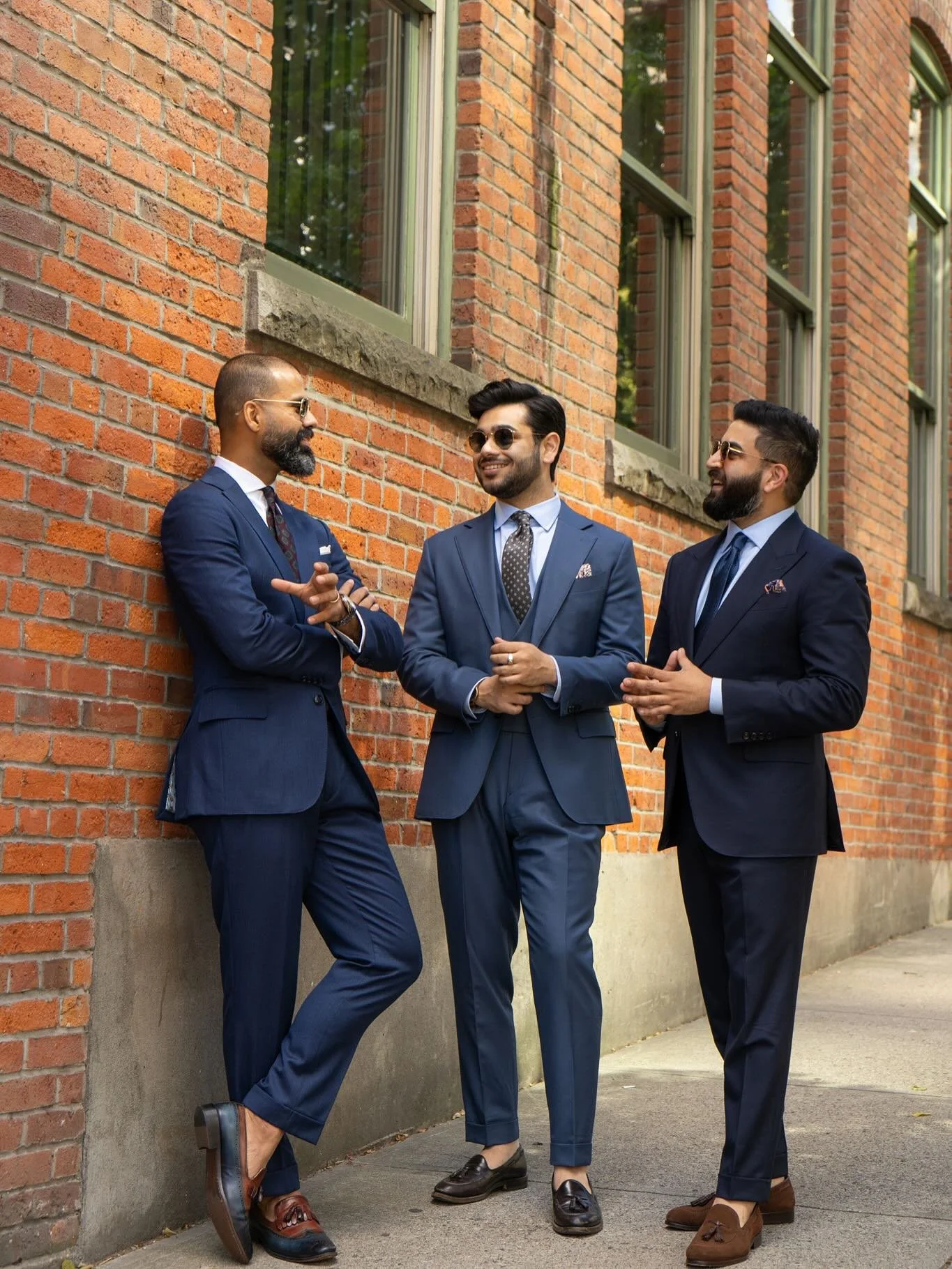Three men in navy bespoke business suits outside a brick building in Vancouver