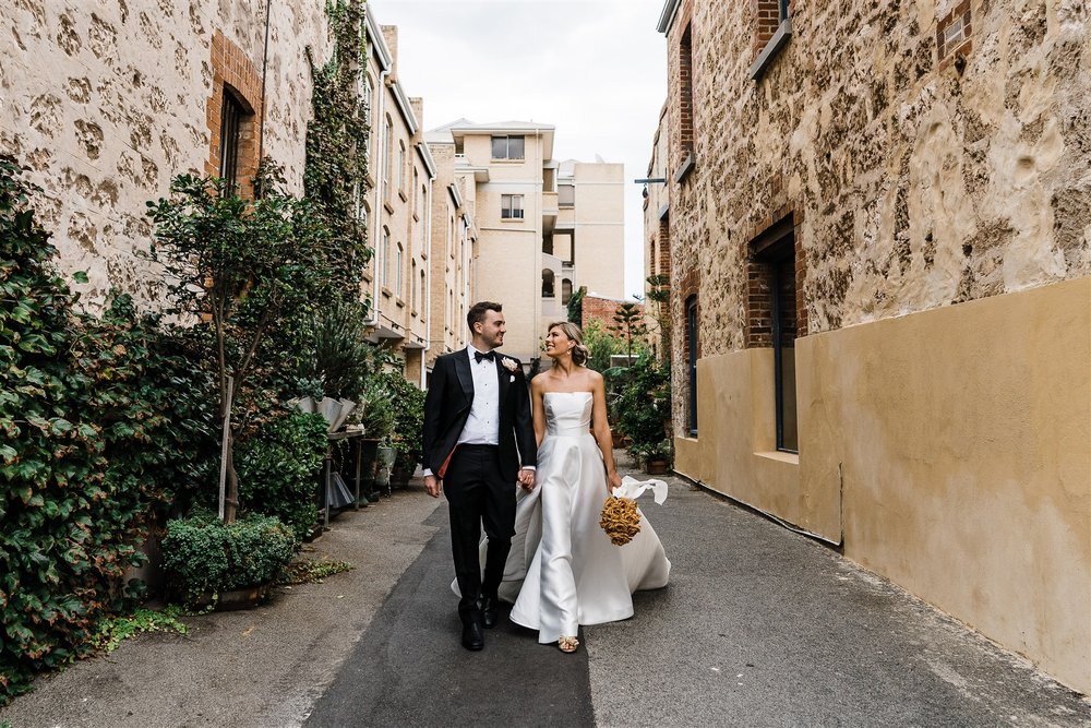  bride and groom walking hand in hand in their wedding at Assembly Yard in Fermantle, Australia 