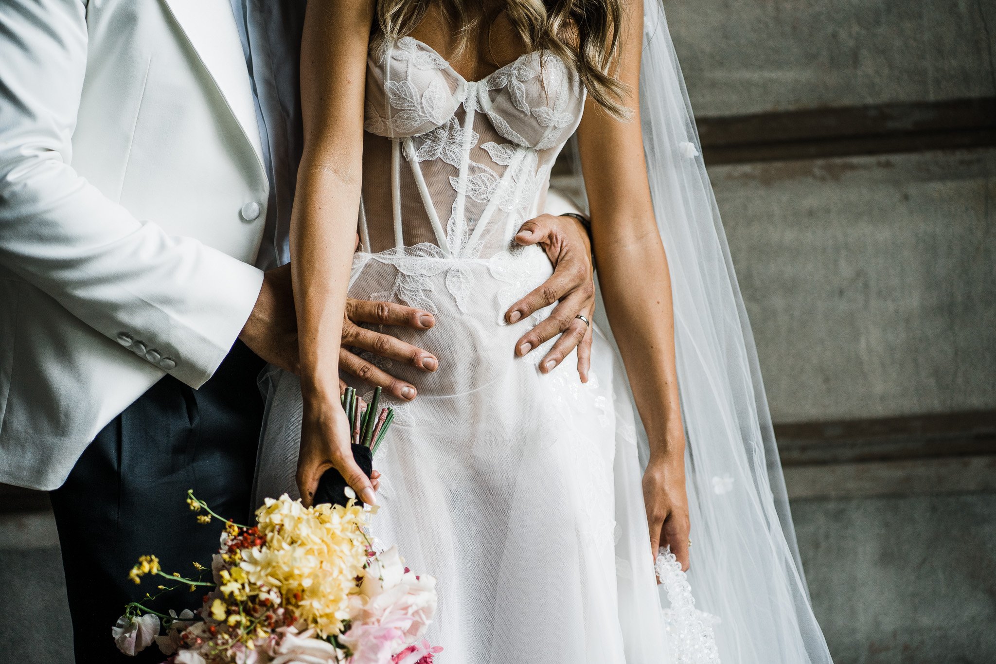  bride wearing modern wedding dress and groom wearing white suit 