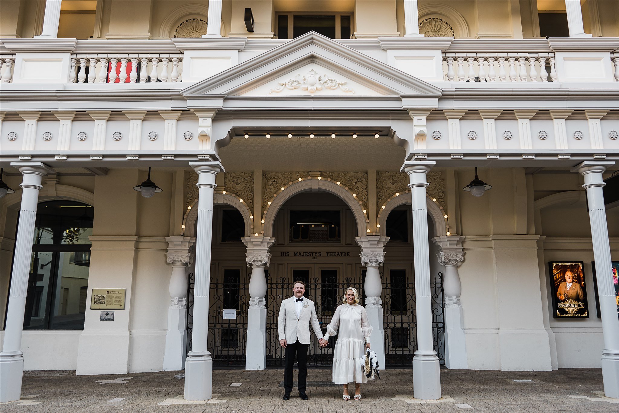  couple standing and holding hands in front of Melbourne hotel 