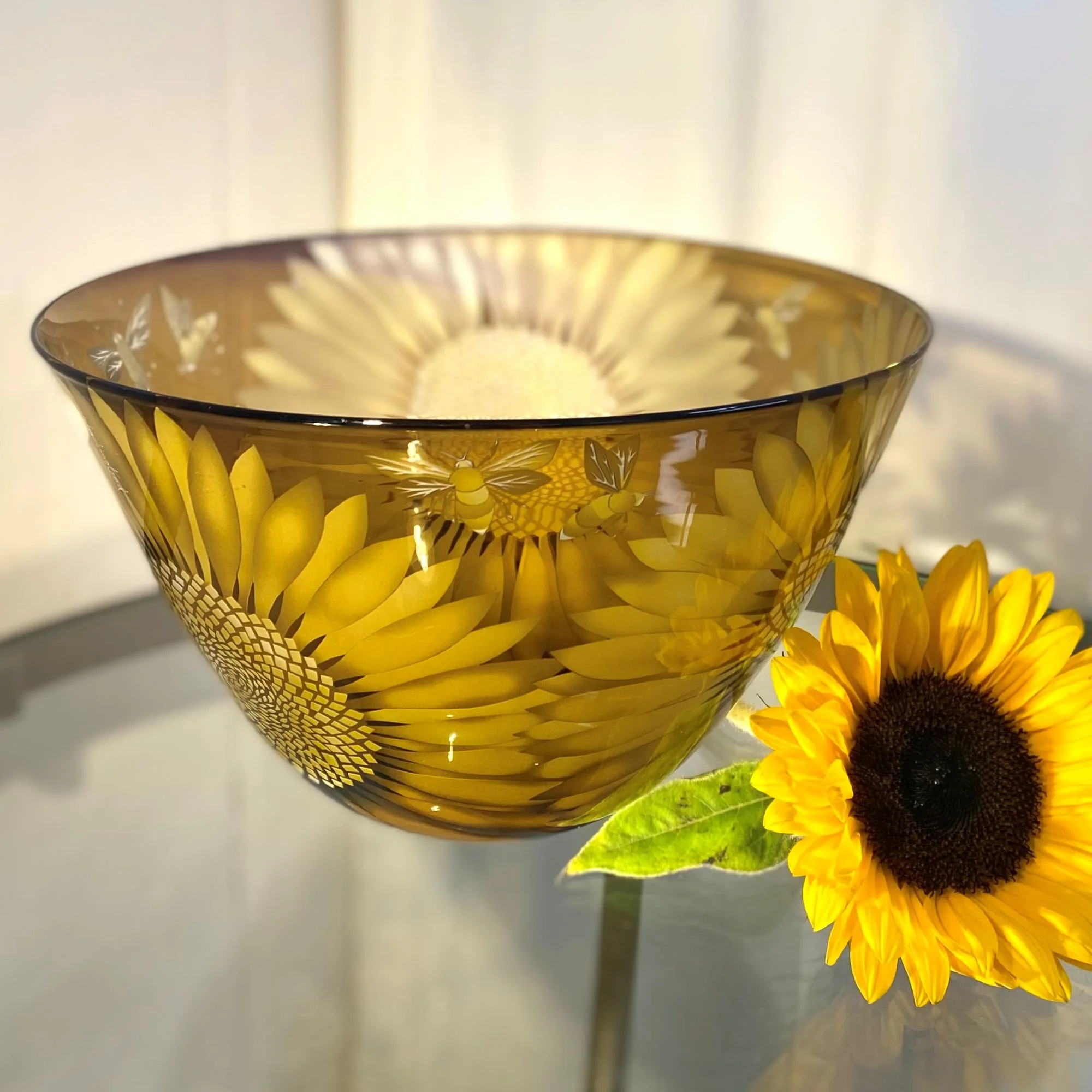 A rich bowl in golds and browns decorated with three sunflower heads and bees by Julia Linstead, Glass