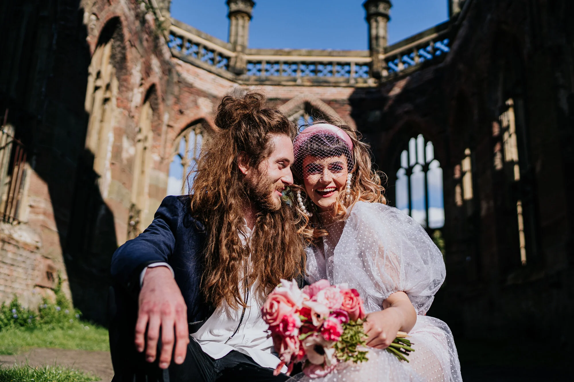 Bride and groom sat laughing in The Bombed Out Church an alternative Liverpool wedding venue
