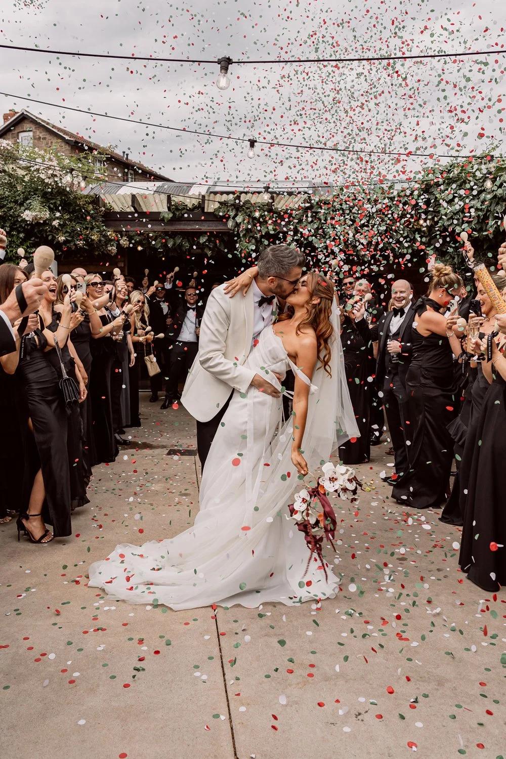 bride and groom kissing under confetti on their alternative wedding day