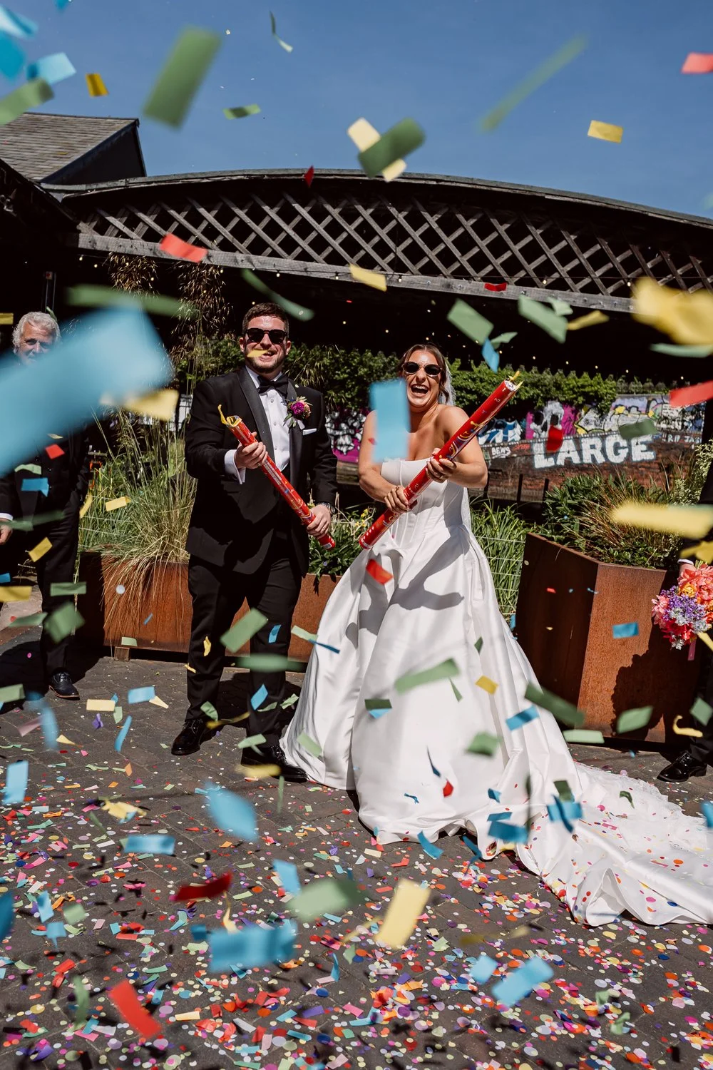 Bride and groom setting of colourful confetti canon on their wedding day in Digbeth