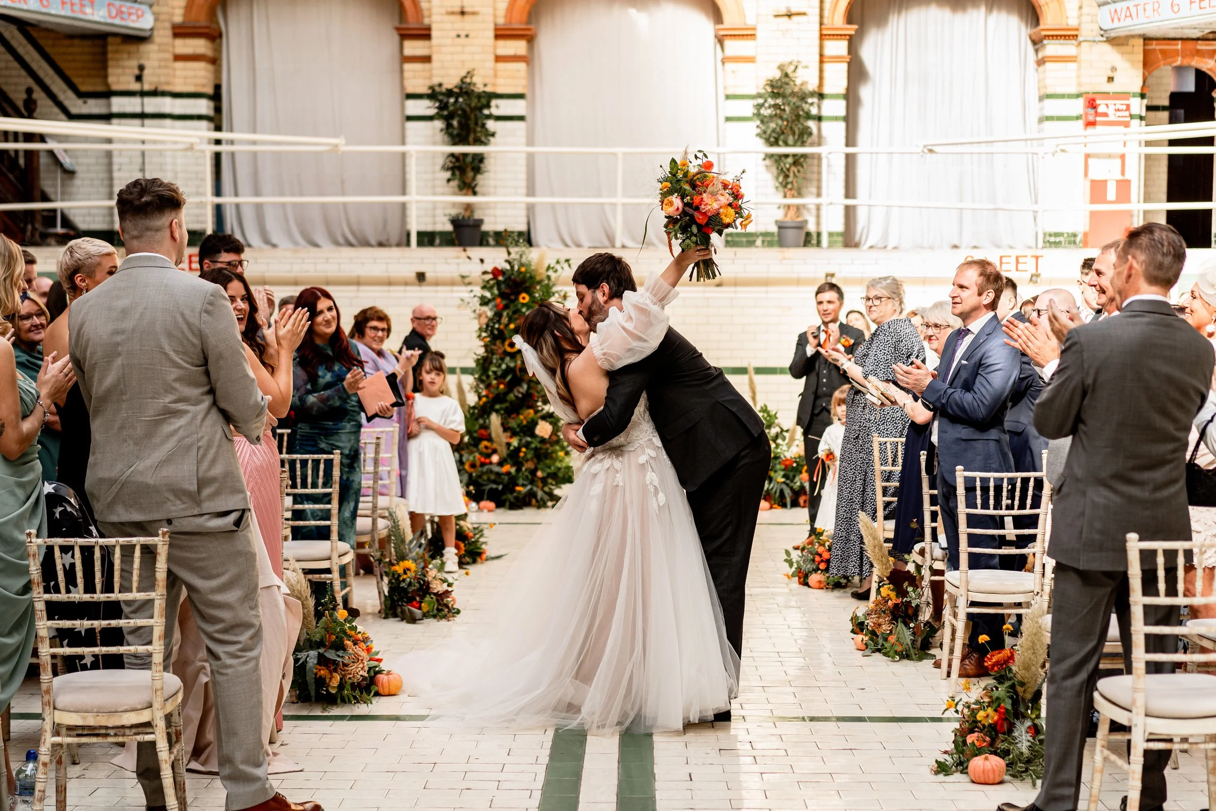 Bride and groom having a kiss as they walk up the aisle on their non traditional wedding day in Manchester