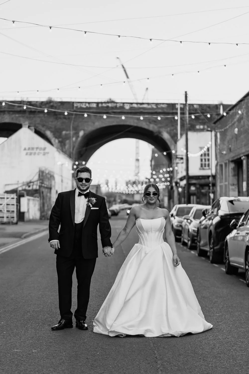 Bride and groom looking down the camera as they stand in the streets of Digbeth on their wedding day