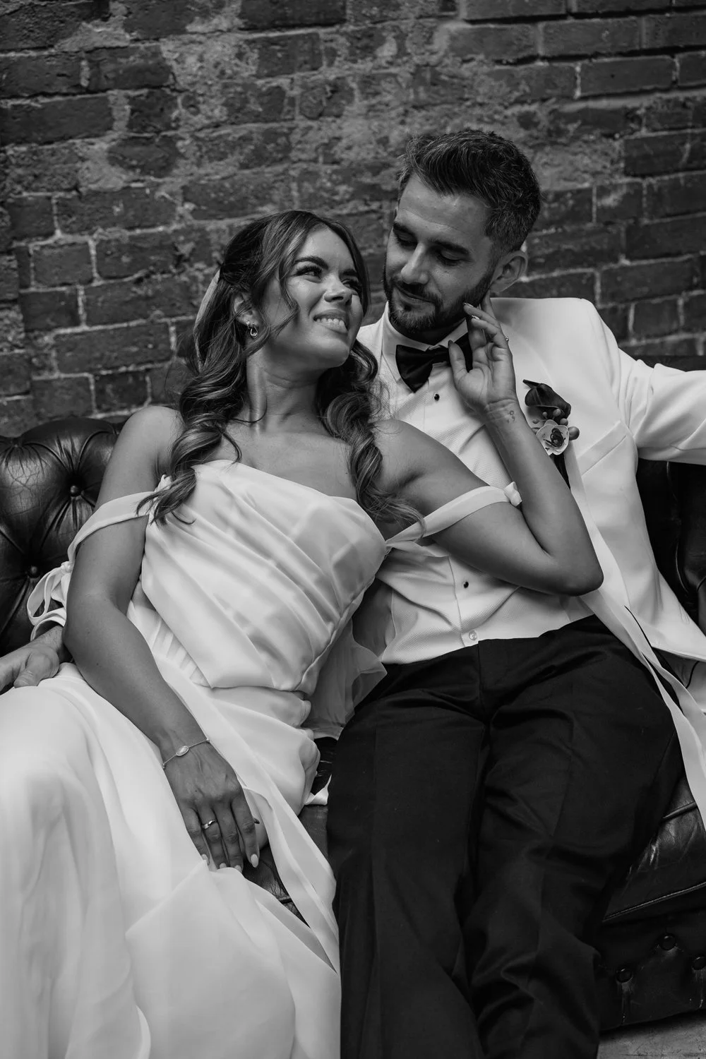 bride and groom sat on sofa looking at each other 