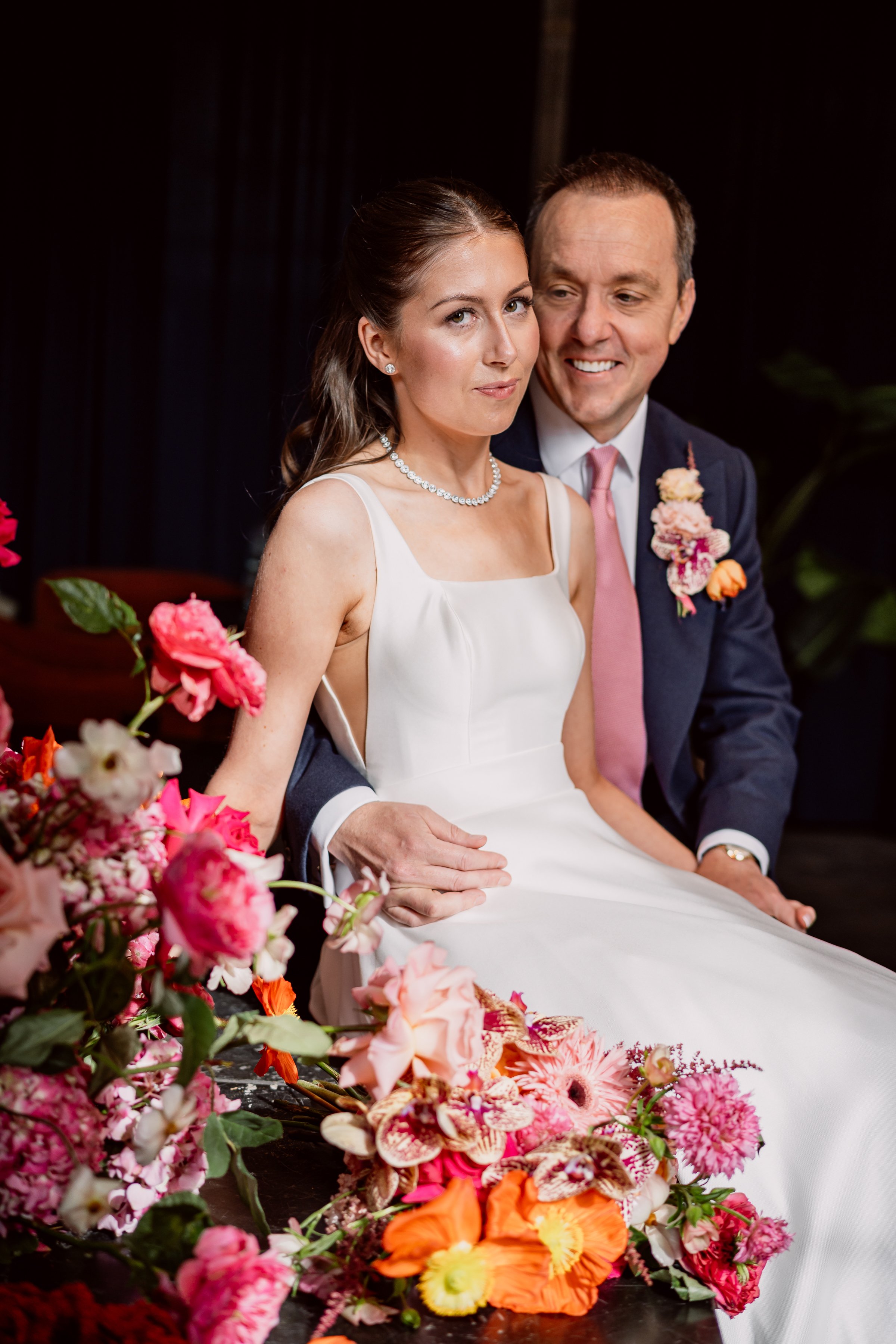 Bride and groom sat amongst flowers on. their wedding day at Kindred in London
