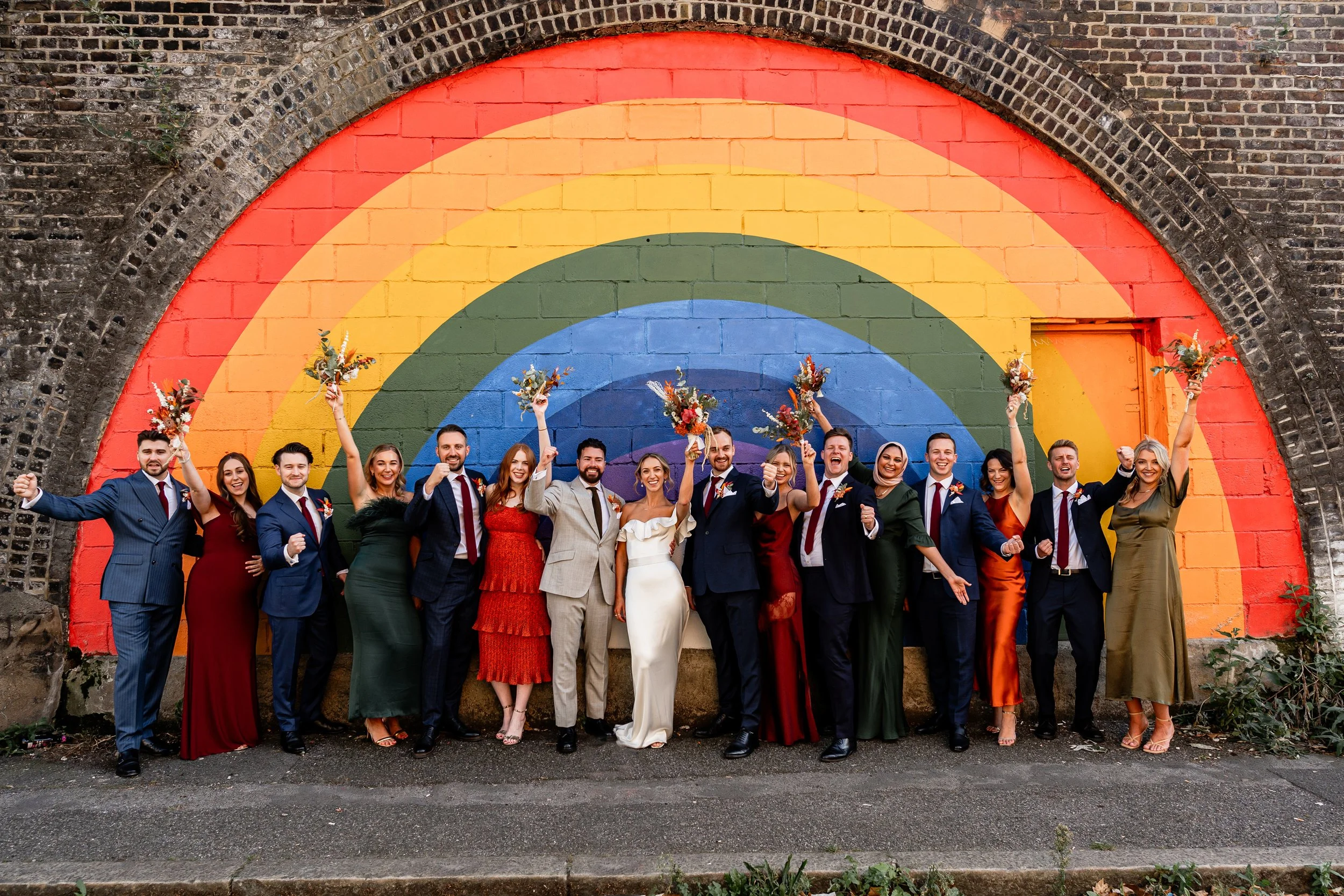 Wedding guests and the couple posing in front of colourful wall during their during their urban city wedding