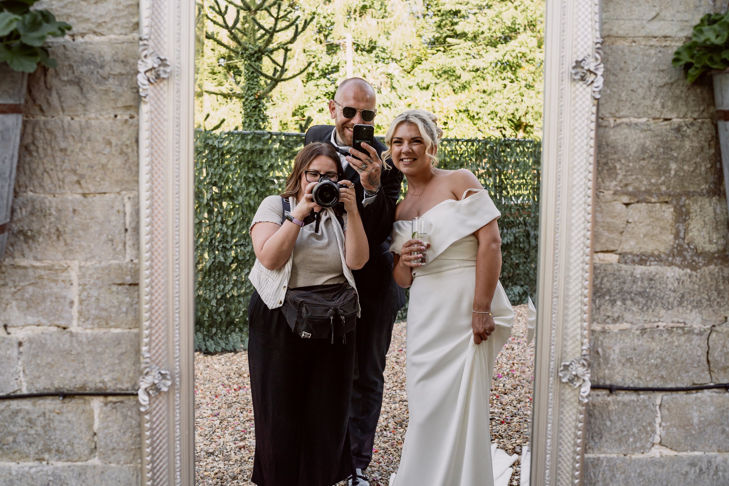 A photo of Steph a Birmingham wedding photographer with bride and groom in a mirror on their wedding day