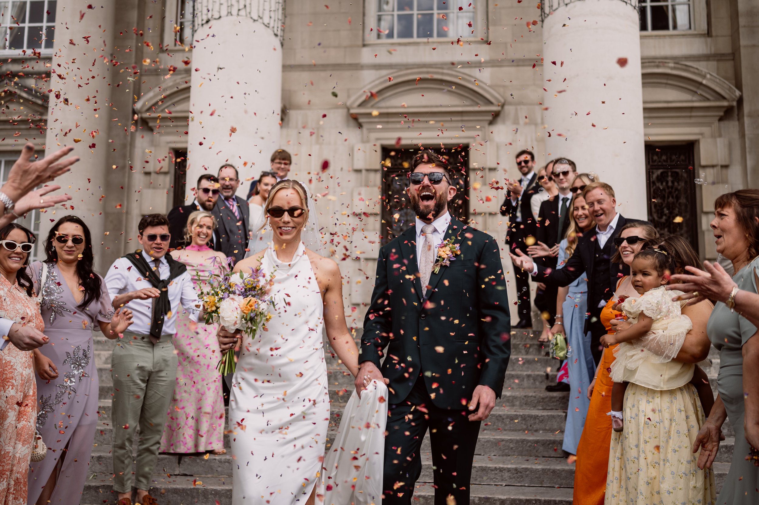 Bride and groom laughing through confetti exit in leeds